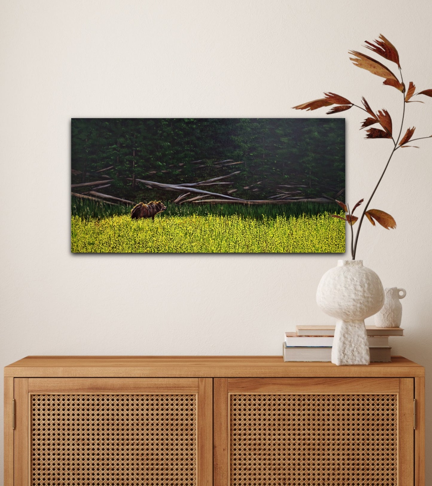 Oil painting of a grizzly bear stepping from a sunlit wildflower meadow into the shadowy calm of a forest, on a wall behind a cupboard