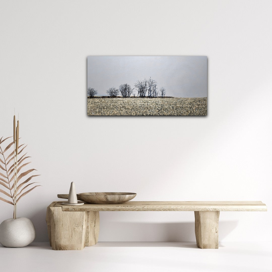 Finter 18"x36" oil painting of a field with winter trees and a blue-grey horizon over a bench on a white wall