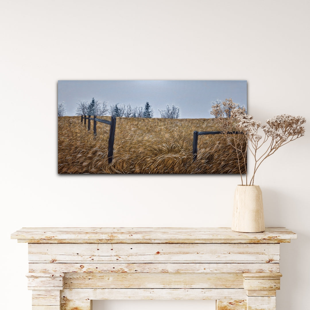 Framed landscape print of a field with trees on a wall above a wooden console table.