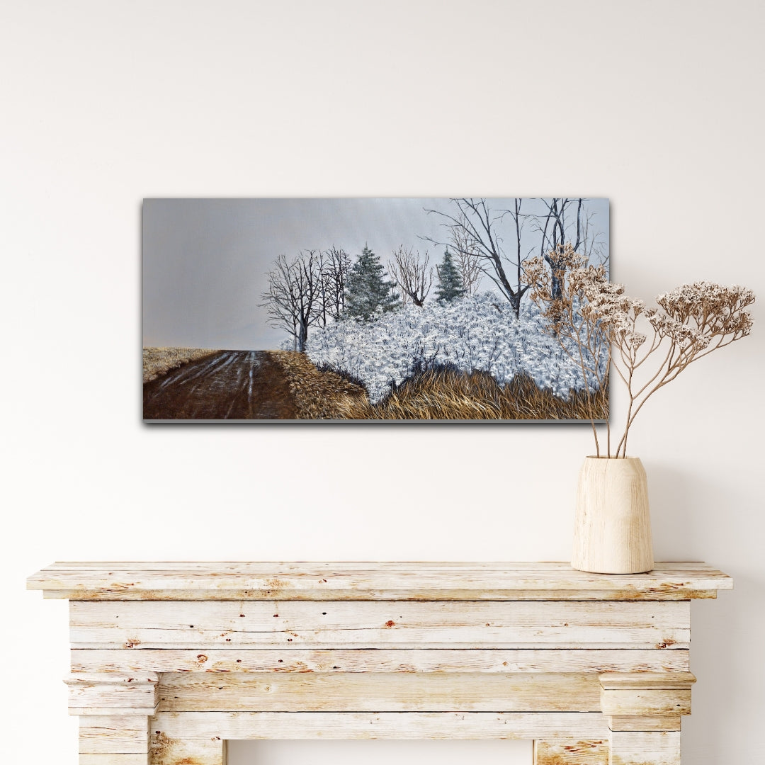 Winter landscape painting on a wall above a wooden console table with a vase of dried flowers.