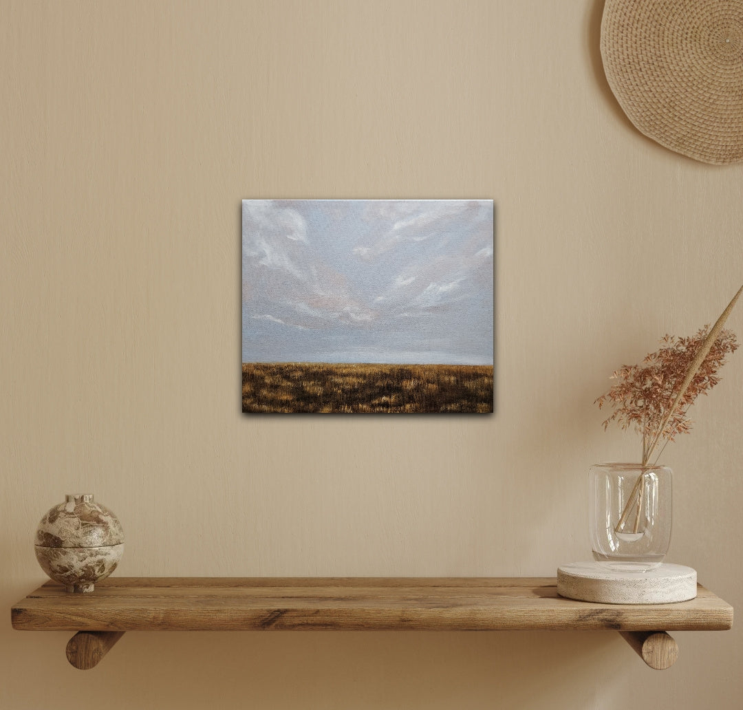 Breathe-oil landscape painting of a soft sky and flat prairie in fall all gold and brown on a yellow wall