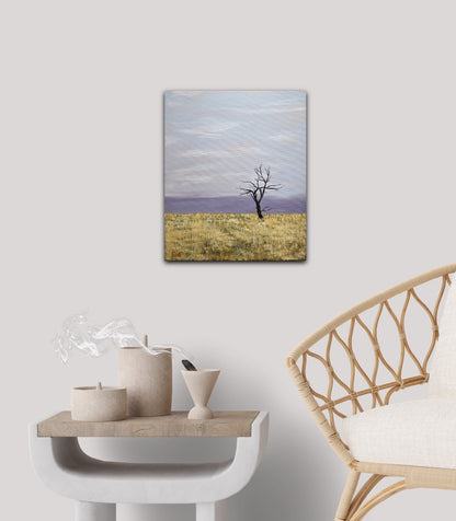 Change - 12"x10" oil landscape painting of a solitary winter tree in a hay field with the cold moving in on the horizon on a white wall