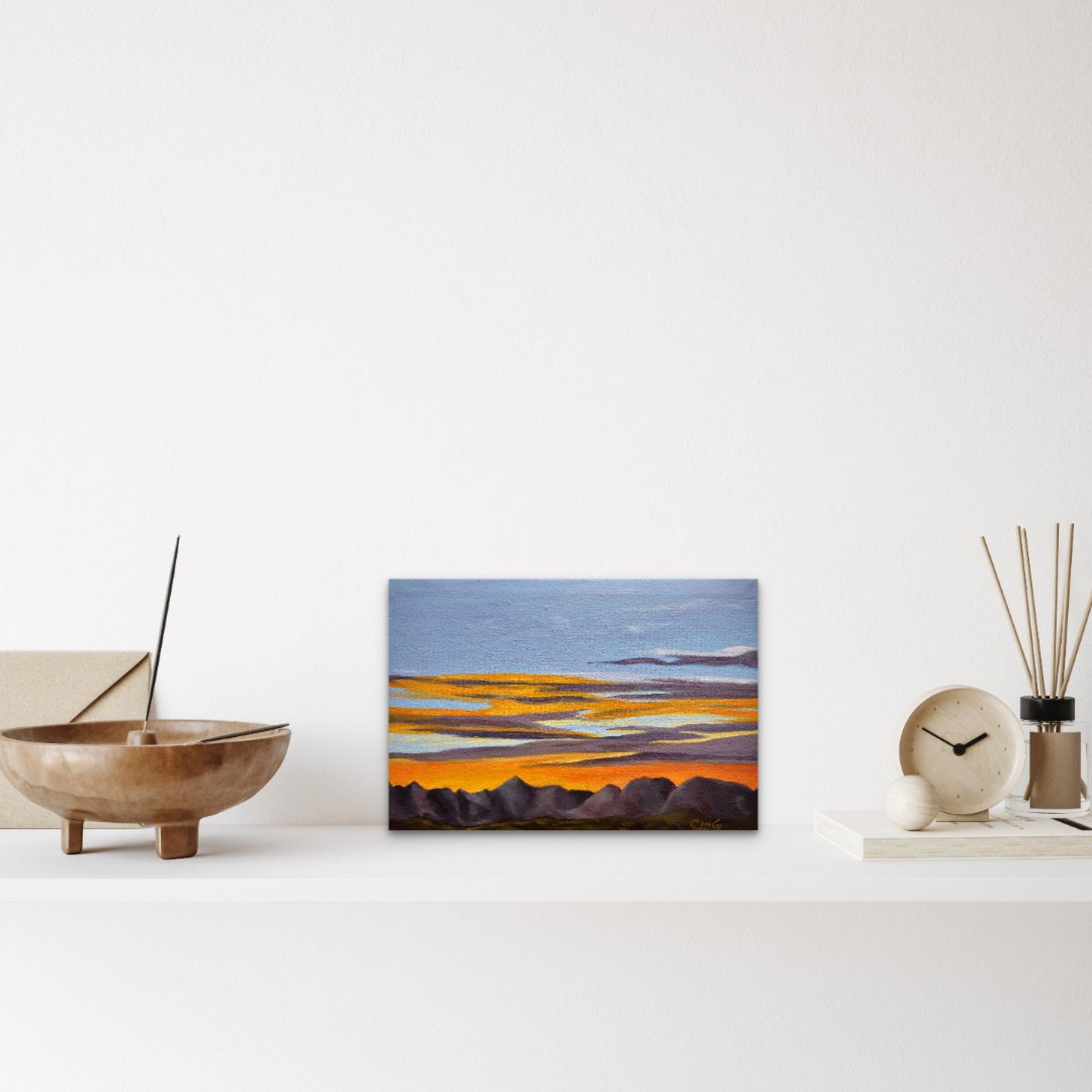 Abstract landscape painting on a white wall with decorative items below.
