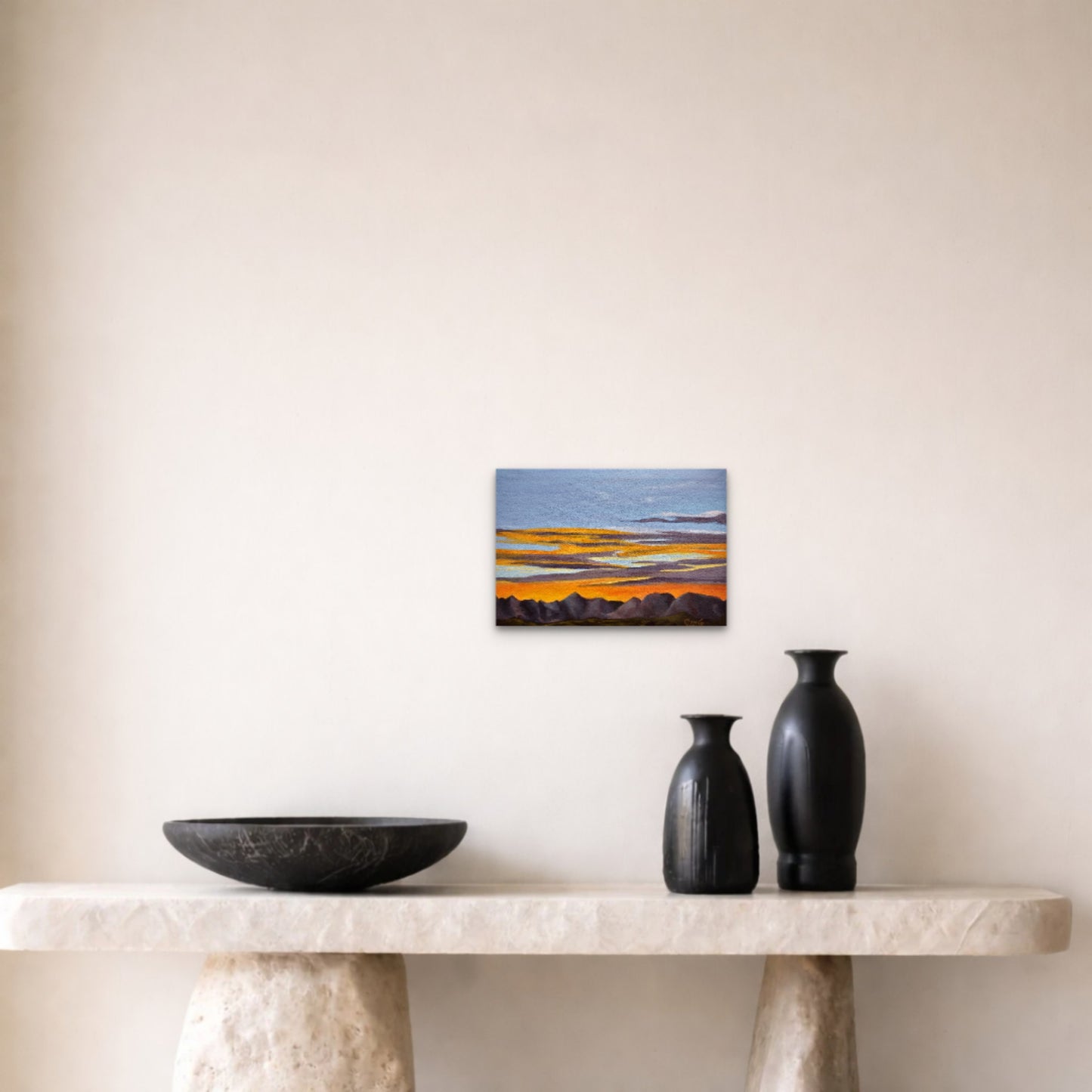 Small abstract painting on a wall above a marble ledge with two black vases and a bowl.