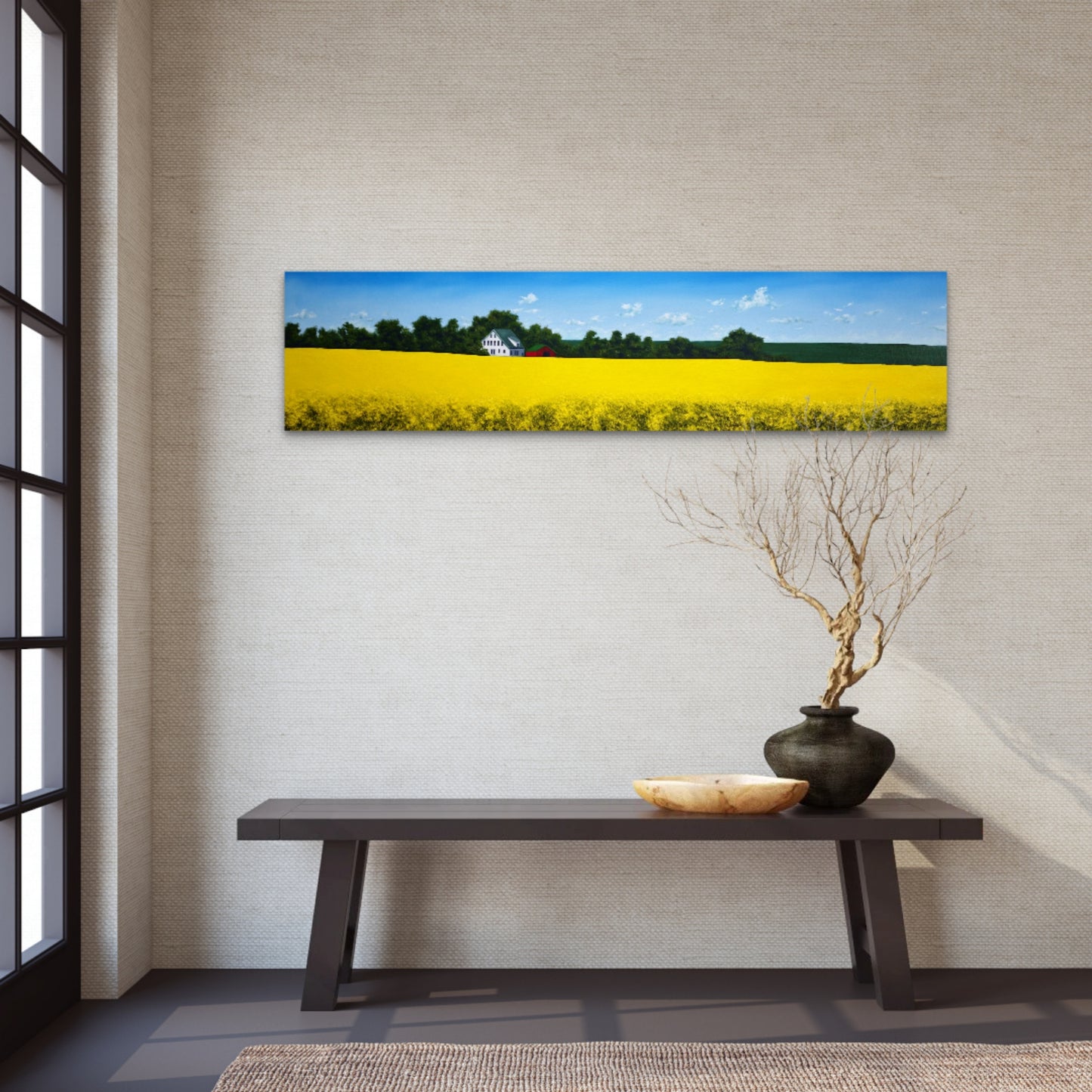 Panoramic landscape painting of a yellow field on a wall above a wooden bench with decorative items.