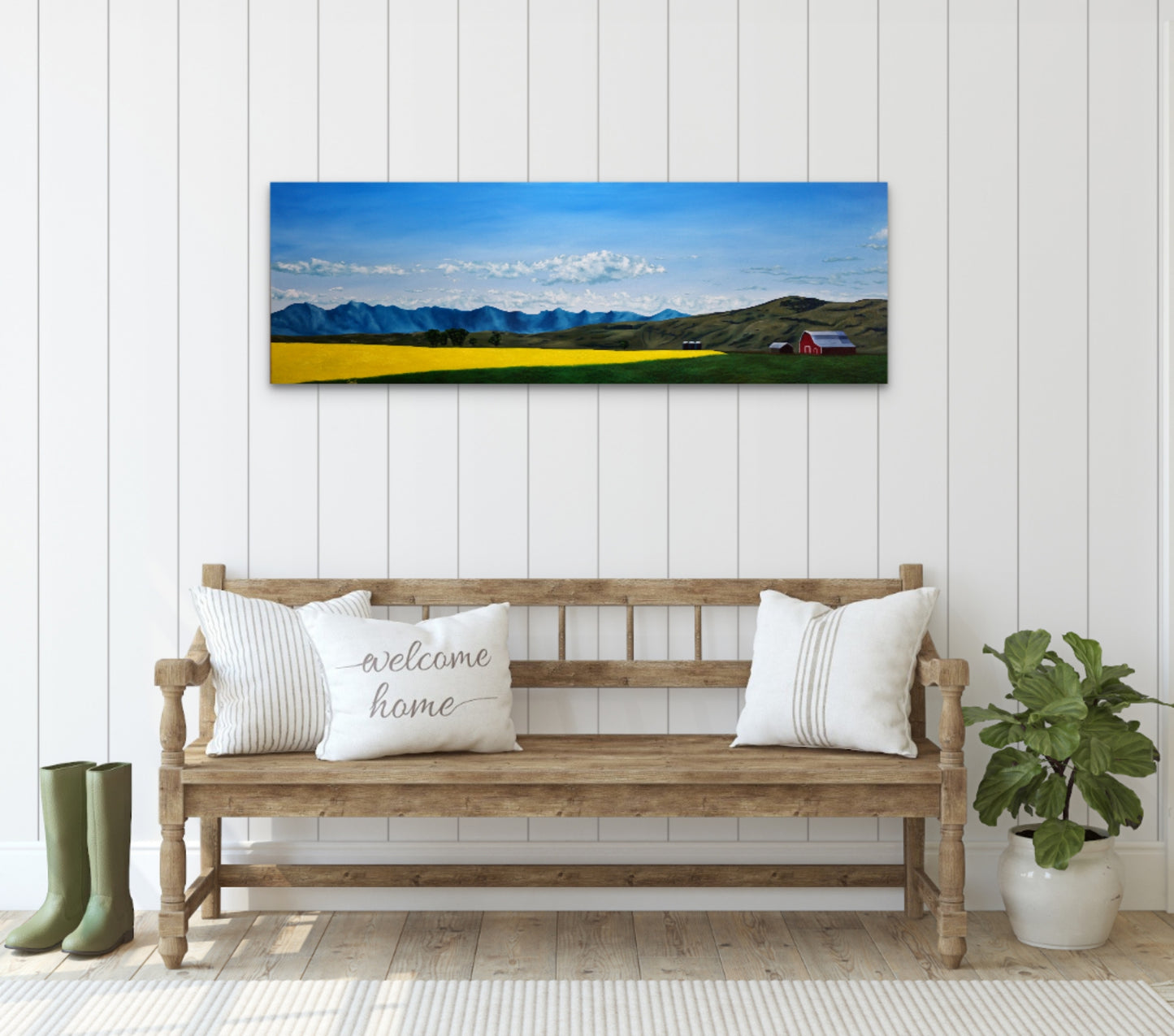 Wooden bench with decorative pillows in a room with a large landscape painting on the wall.