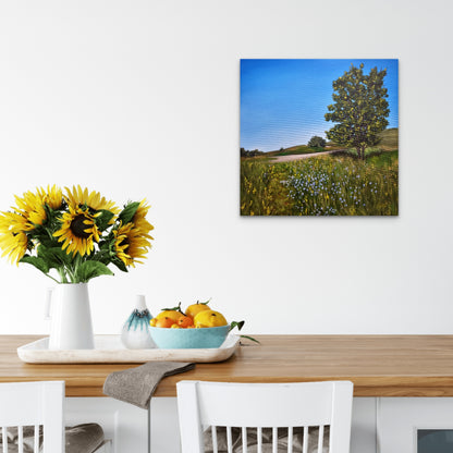 Dining table with sunflowers, fruit bowl, and a wall art of a tree in a field.