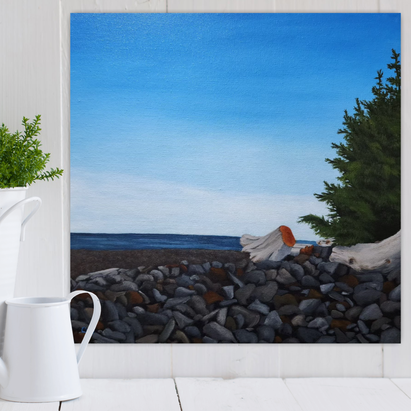 Christina Gouldsborough's original oil landscape painting of a Vancouver Island scene of a misty mid day at the ocean shore, on a white wall, with a plant and water can in white in front on a shelf
