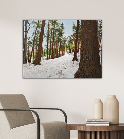 Framed photograph of a snowy forest scene on a wall above a chair and table.